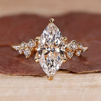 Marquise cut engagement ring with round cut side stones in a diamond ring design with a cluster setting.