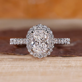 Elongated cushion engagement ring with halo diamond and pave setting details.