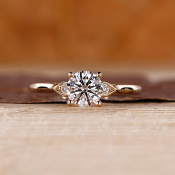 3 stone round diamond ring with cathedral setting and pear shape outline.
