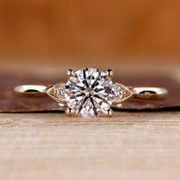 3 stone round diamond ring with cathedral setting and pear shape outline.