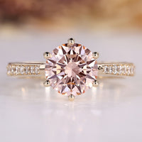 Round diamond ring with pink center stone and tapered shank.