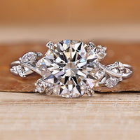 Nature inspired engagement ring with round center stone and marquise and round side stones.