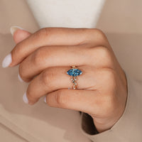 Blue marquise engagement ring with six leaf style prongs.