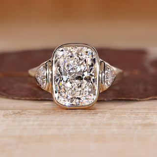 Three diamond ring with cushion cut center diamond and trillion side diamonds.