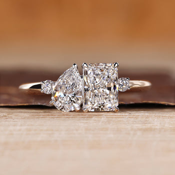 Two stone ring with pear and radiant cut diamonds and round side stones.