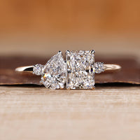 Two stone ring with pear and radiant cut diamonds and round side stones.