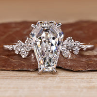 Cluster diamond ring with coffin center stone and round side stones.