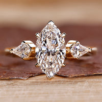 Three stone ring featuring marquise diamond and kite cut side stones.