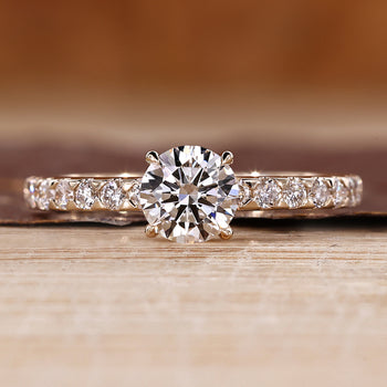 Round cut engagement ring with a pave setting crafted in yellow gold.
