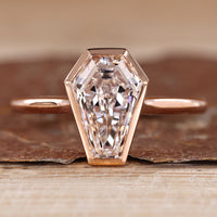 Solitaire diamond ring with coffin cut diamond and bezel setting.