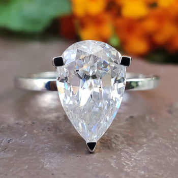 Elegant pear shaped engagement ring displayed on a white satin cloth.