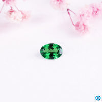 Oval cut gemstone with gemstone green hue.