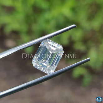 Emerald cut moissanite next to moissanite loose stone.