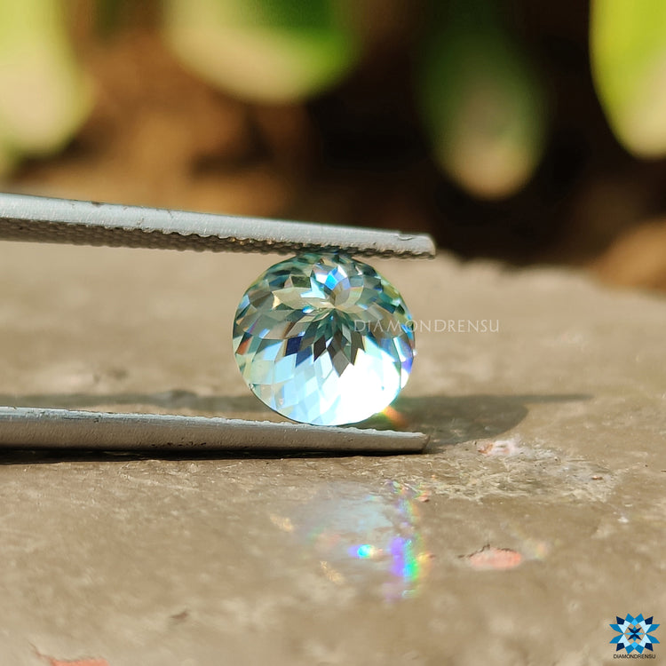 Cyan blue round Portuguese moissanite displayed for rings or pendants.