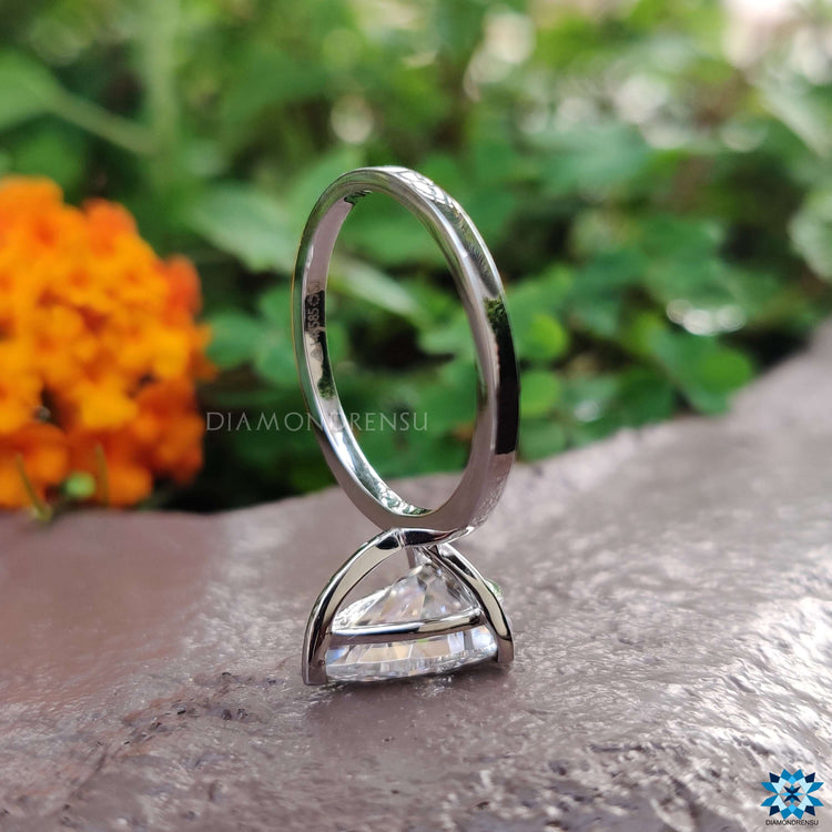 Pear shape engagement ring sparkling under natural sunlight on a velvet cushion.