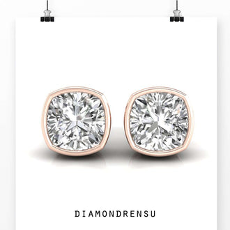 Handmade bezel set stud earrings with cushion cut diamonds for a refined finish.