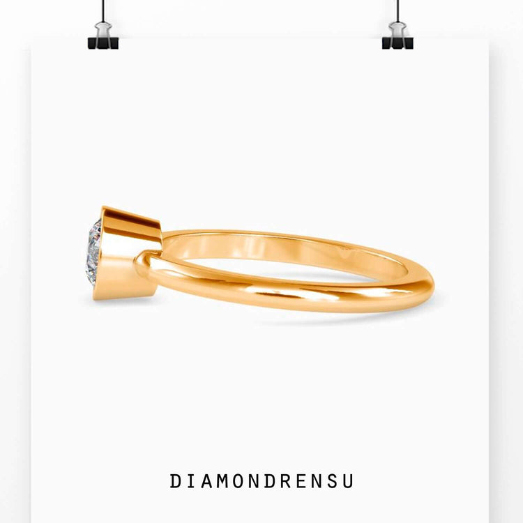 Stunning round solitaire engagement ring with a gold bezel setting for a modern touch.