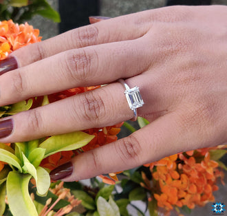 Emerald cut moissanite engagement ring with a radiant solitaire setting.
