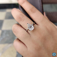 Stunning engagement pear shaped ring set against a romantic floral backdrop.