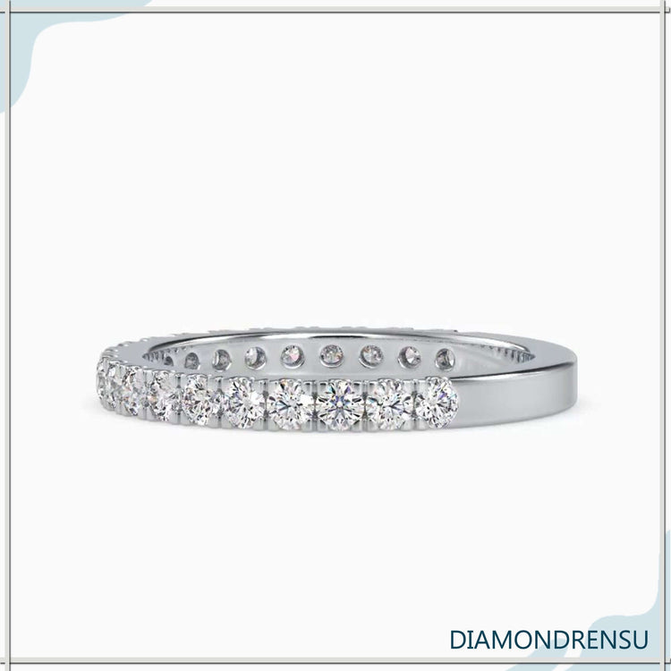 Pave wedding band featuring round diamonds in a gold band with prong tab settings.