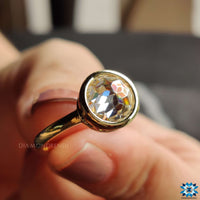 Round bezel engagement ring with a sparkling moissanite centrepiece.