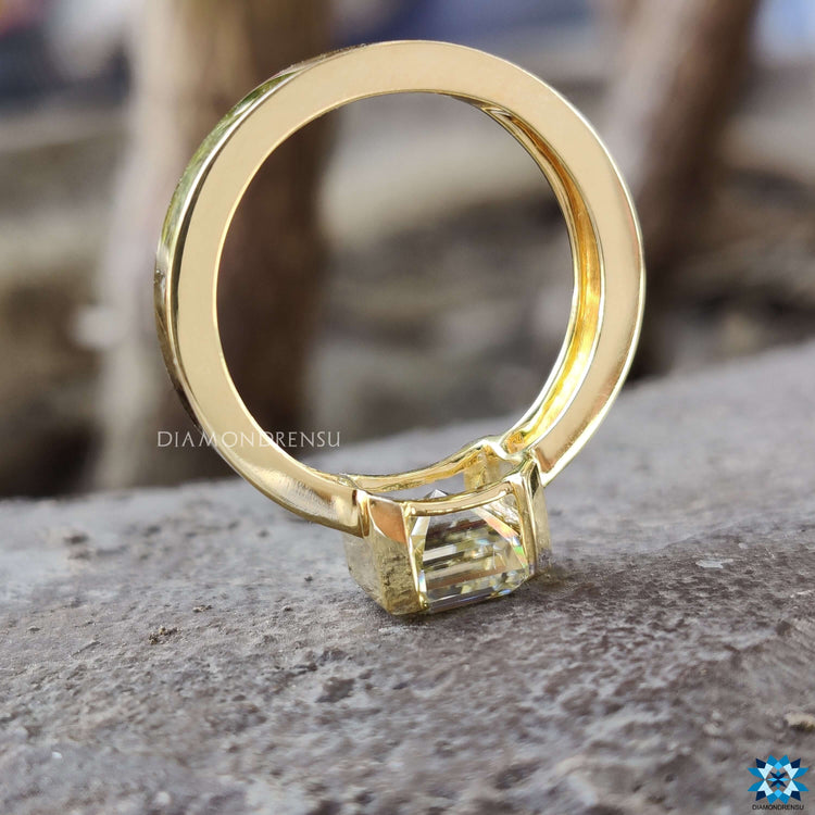 A unique half bezel set ring featuring a radiant moissanite gemstone.