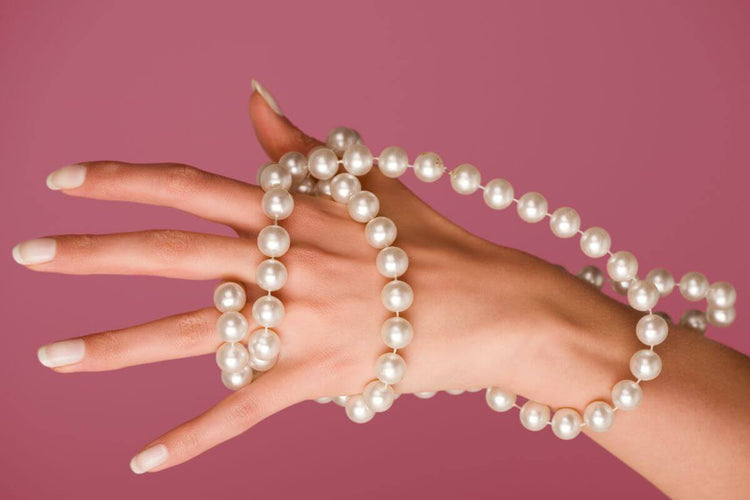 A pearl necklace wrapped around a womans hand