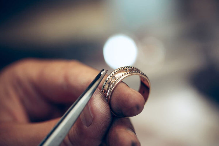 A jeweler setting diamond on the gold ring.