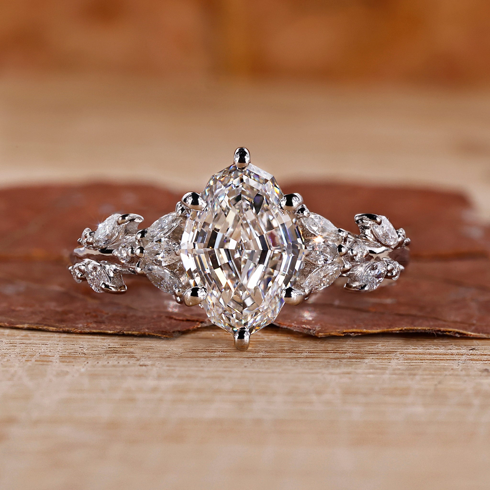 Close-up of a nature inspired engagement ring with intricate details and a step cut oval diamond.