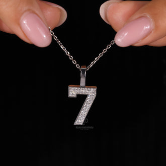 Handmade round diamond pendant with number '7' design in white gold.
