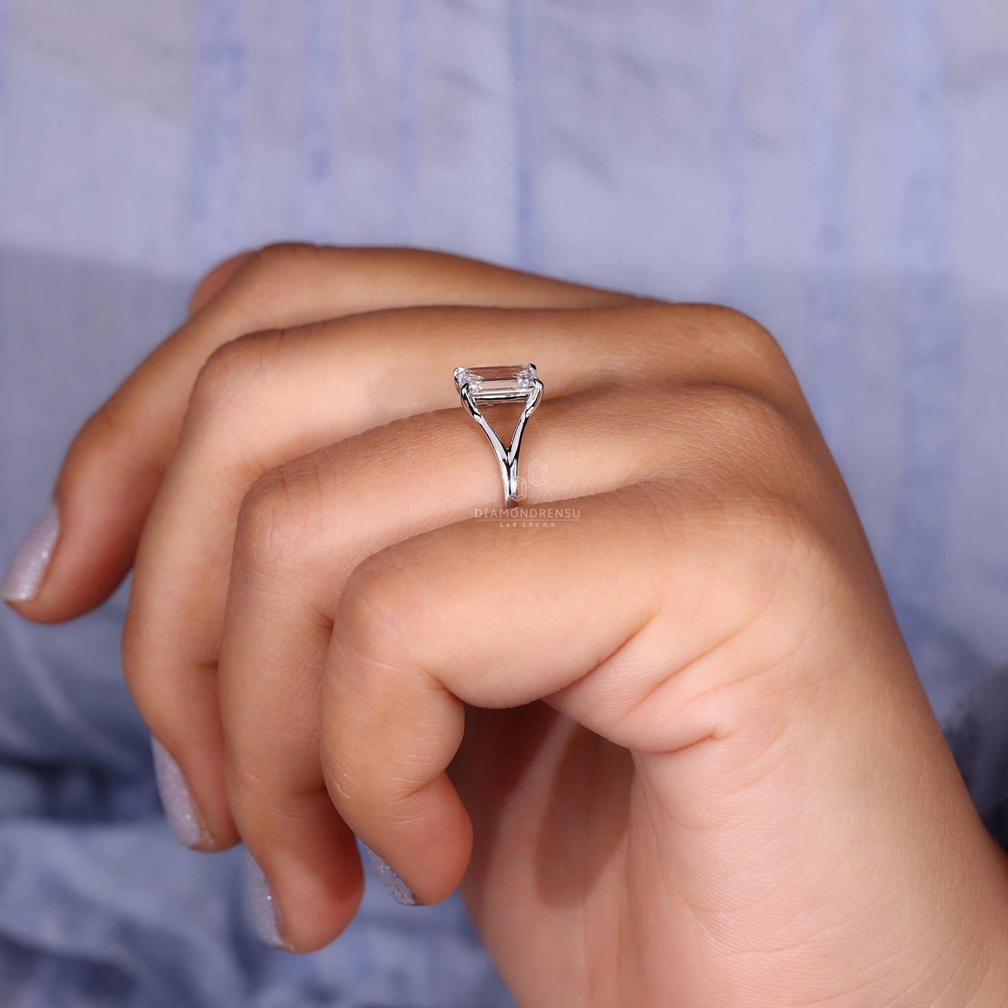 Model displaying an emerald cut lab grown diamond ring on her hand.