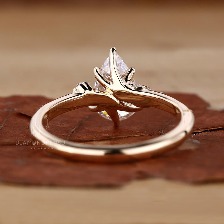 Detailed view of pear cut diamond ring featuring claw prongs and marquise sidestone.