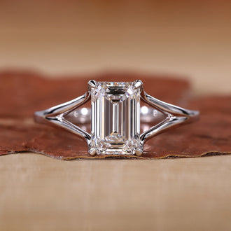 Close-up of emerald cut solitaire ring with claw prongs and white gold band.