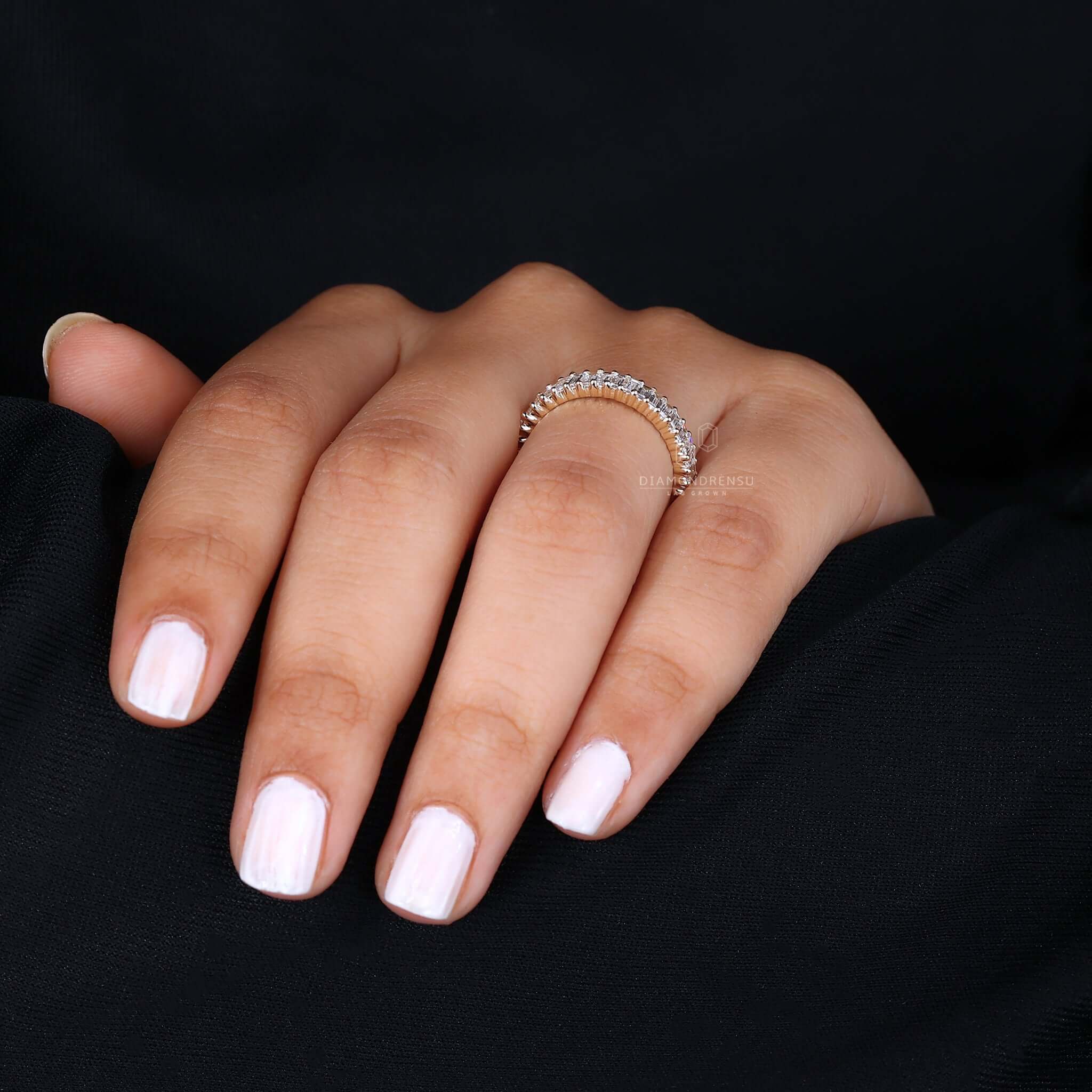 Woman's hand gracefully wearing a lab-grown diamond wedding band, showcasing its beauty and charm