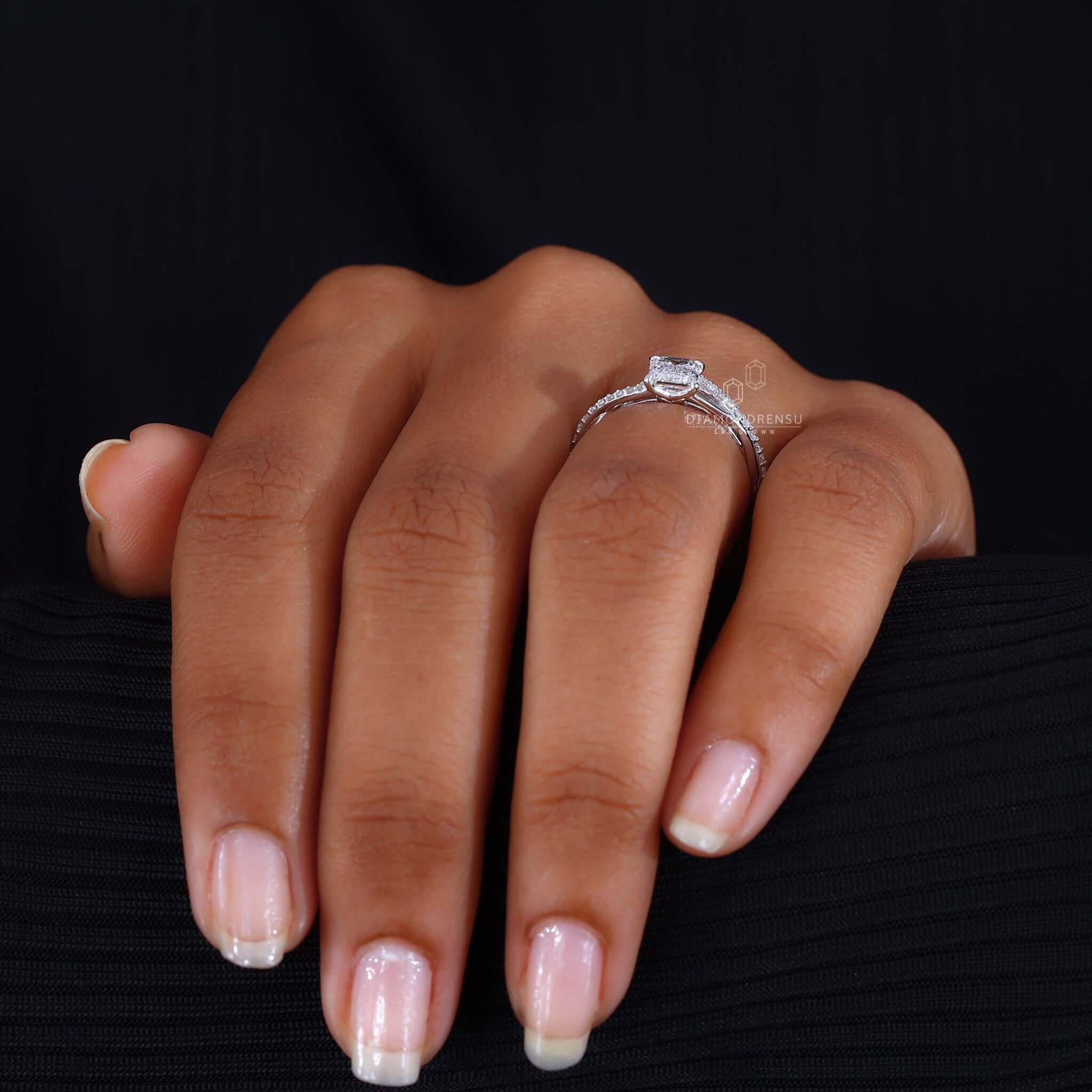 Woman's hand wearing an emerald cut diamond engagement ring, showcasing its timeless elegance