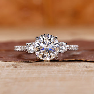 Elegant 3 stone diamond engagement ring with a milgrain band.