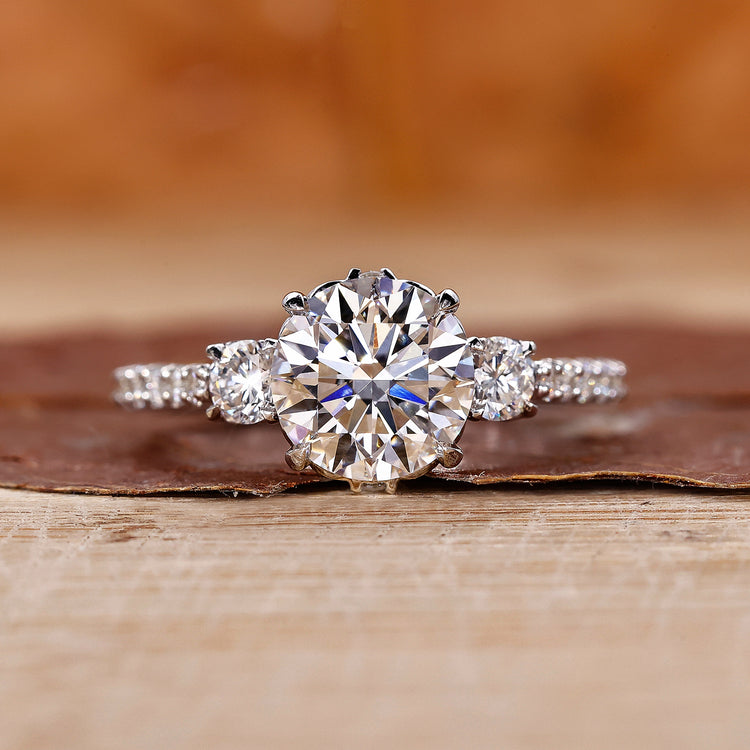 Elegant 3 stone diamond engagement ring with a milgrain band.