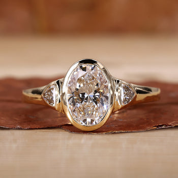 Oval cut bezel engagement ring with side stones
