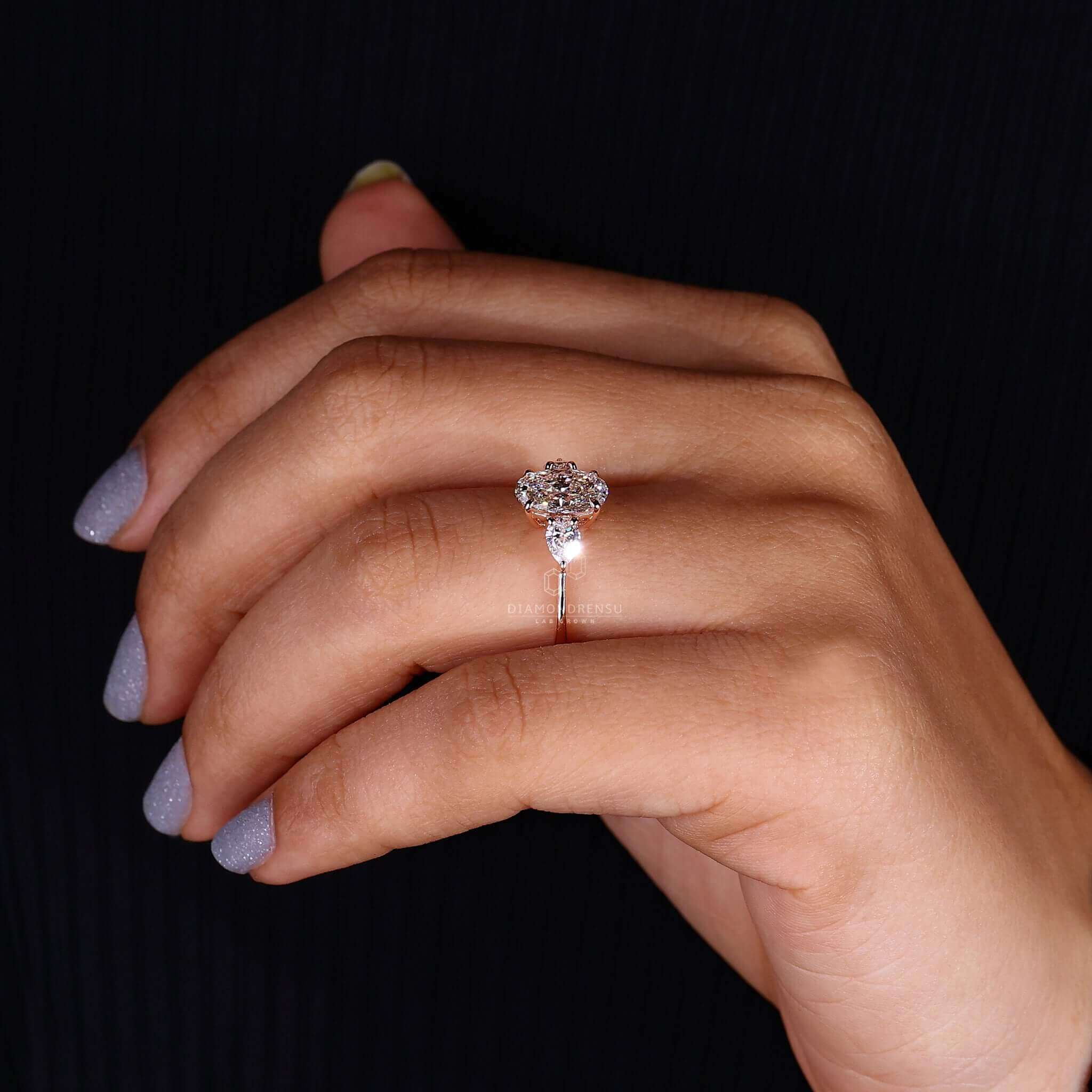 Woman wearing a three stone oval engagement ring with claw prongs