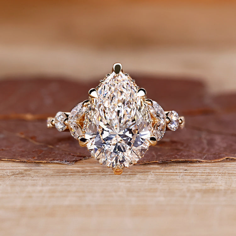 Pear cut diamond ring with hidden halo and marquise side stones.
