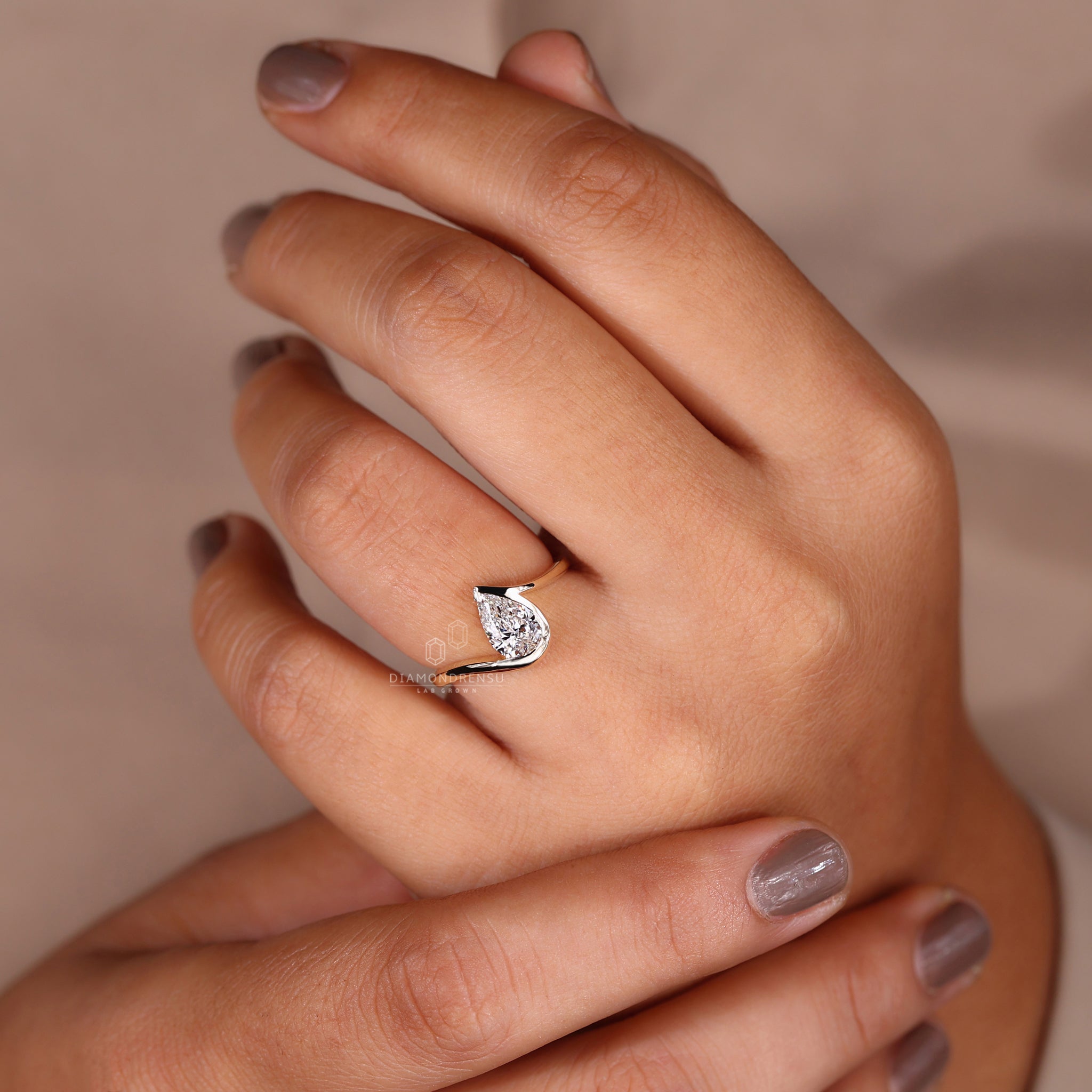 Pear diamond ring with half bezel setting on model’s finger