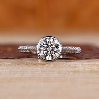 Round cut diamond ring with bezel setting in white gold.
