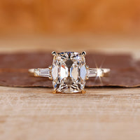 Old mine cushion cut diamond ring with tapered baguette side stones, offering a unique design.
