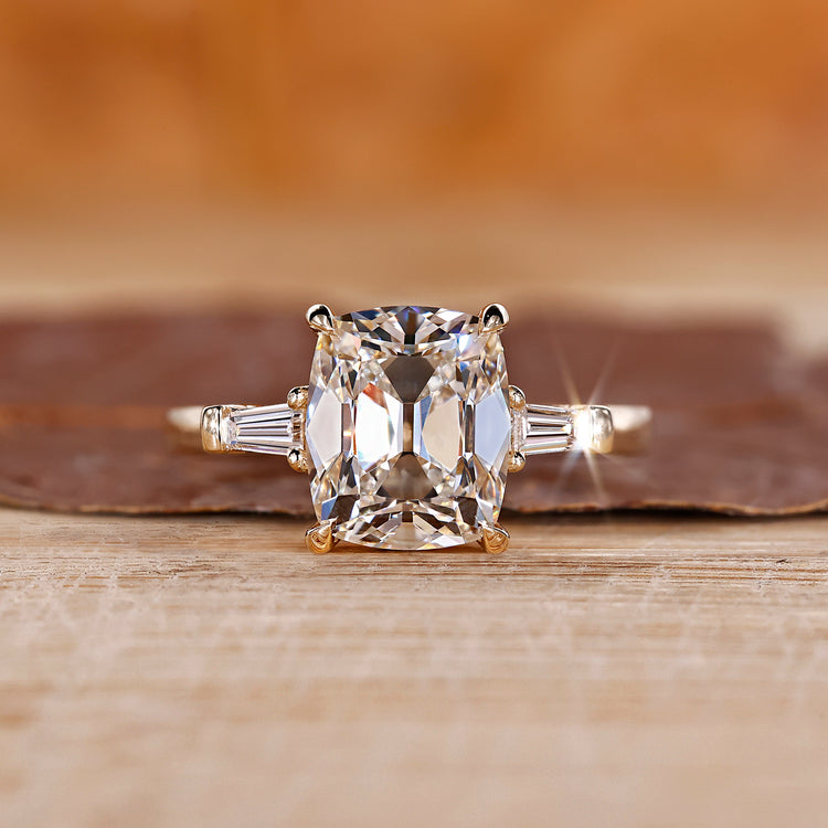 Old mine cushion cut diamond ring with tapered baguette side stones, offering a unique design.
