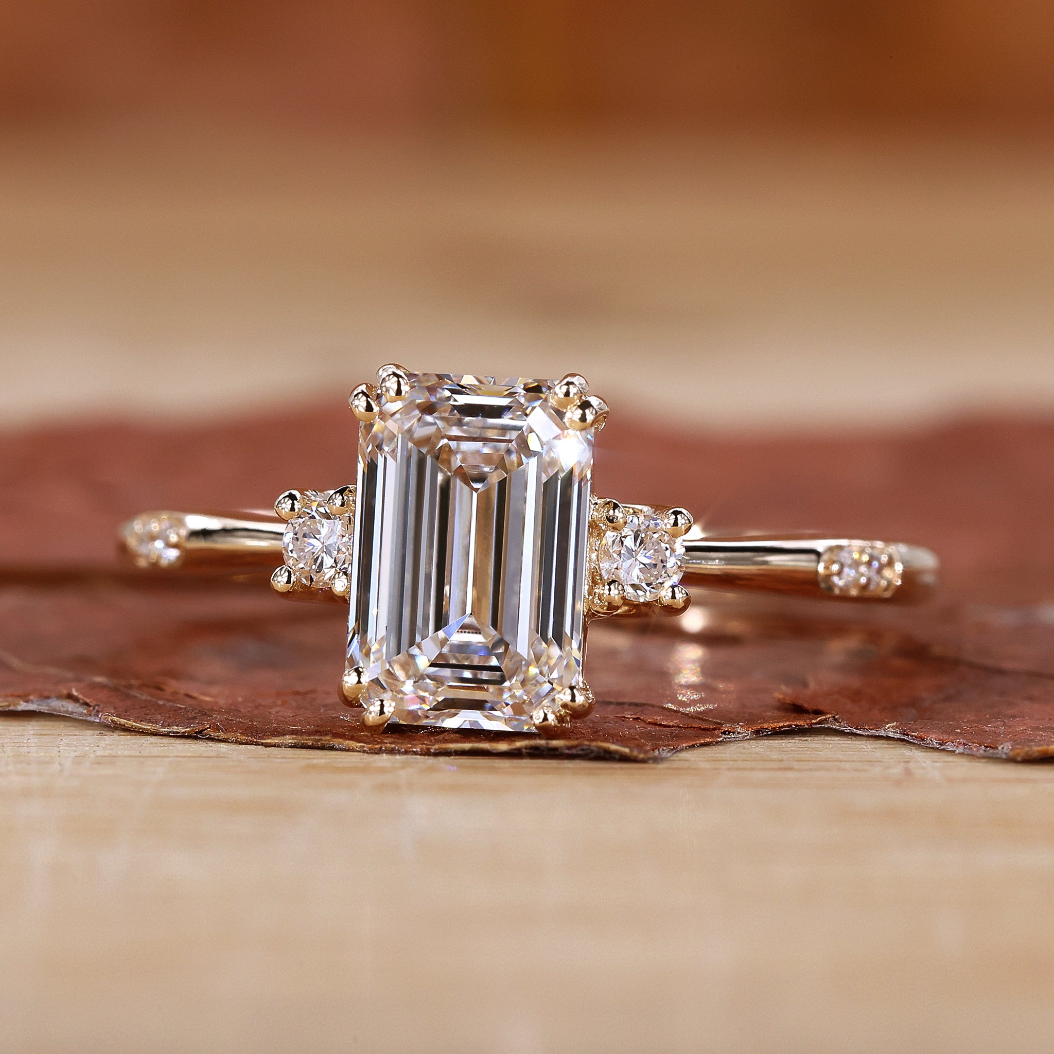 Close-up of a three stone emerald cut ring on a velvet cushion.