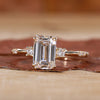 Close-up of a three stone emerald cut ring on a velvet cushion.