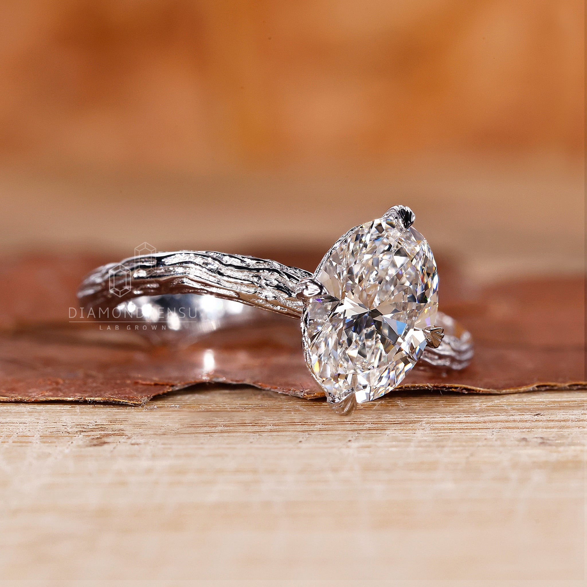 Close-up view of a solitaire oval engagement ring featuring a lab-grown diamond. The diamond is set in a nature-inspired band with claw prongs, IGI certified by Diamondrensu.