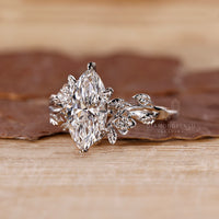 White gold engagement ring featuring a marquise diamond and round side stones for a balanced design.
