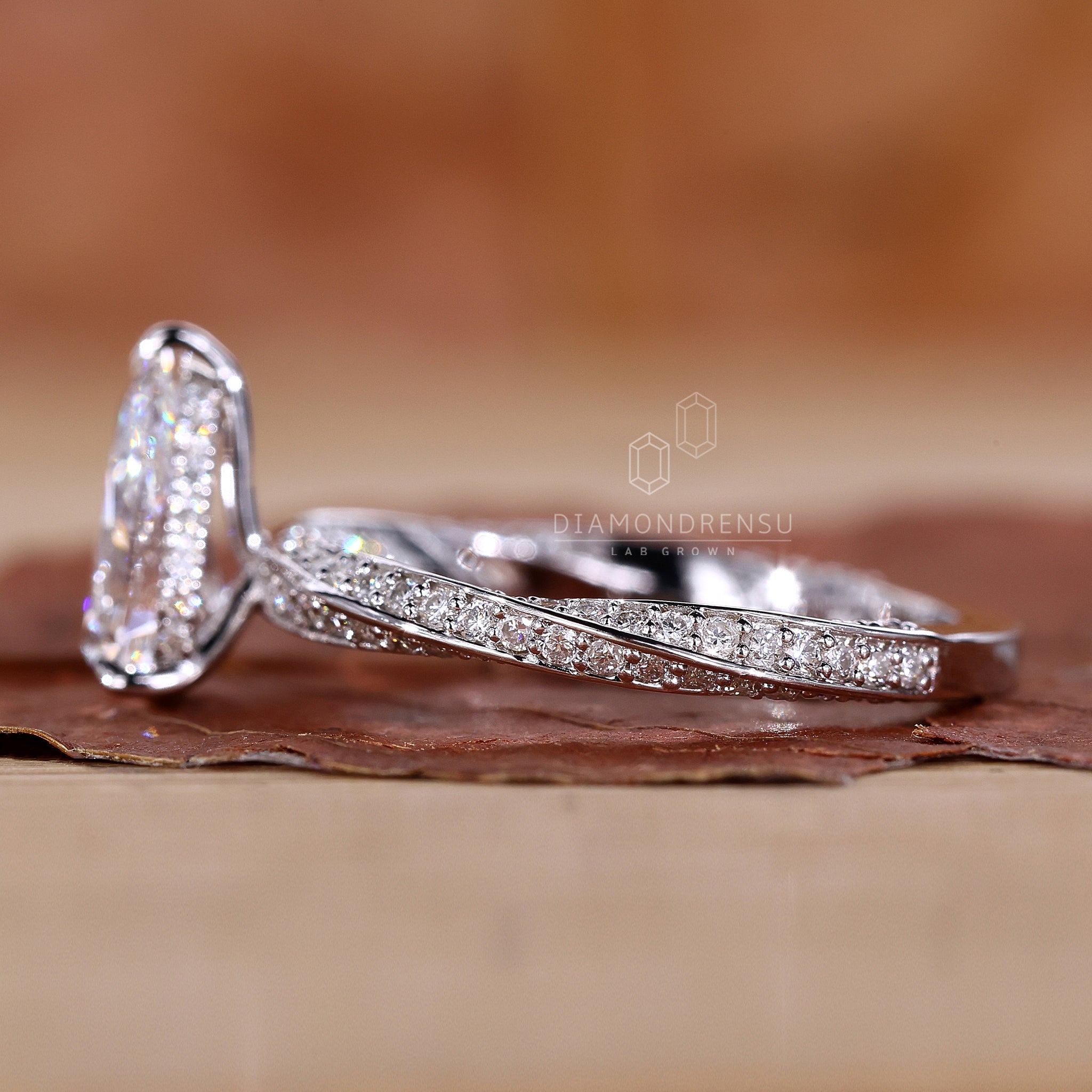 Pear cut engagement ring with a twisted diamond pave band.