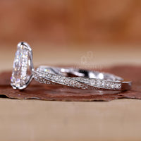 Pear cut engagement ring with a twisted diamond pave band.